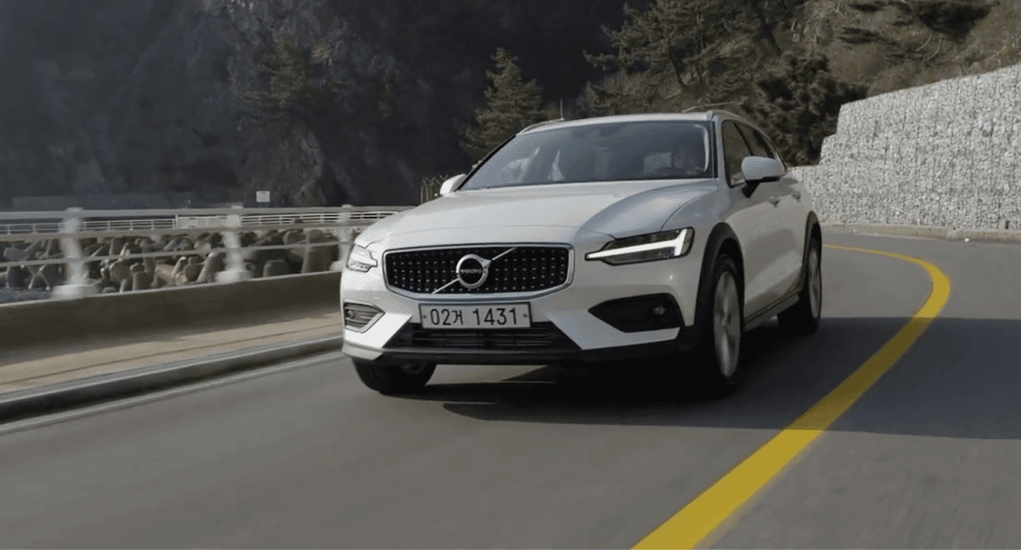White Volvo V60 driving along a coastal mountain road in South Korea, frame from the commercial